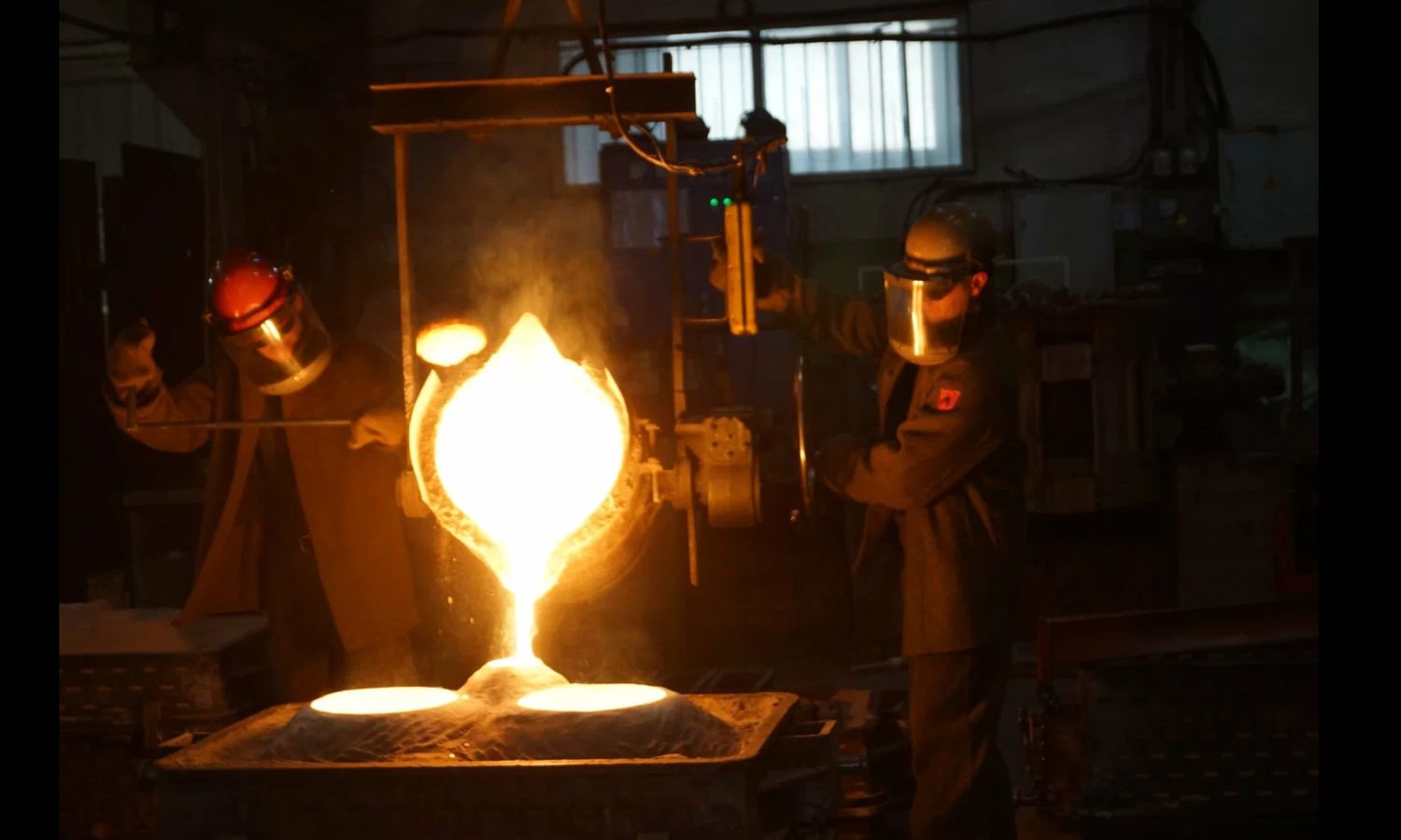 Molten metal poured from a ladle into a sand mould on the foundry floor